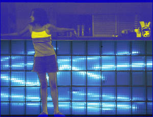 Young woman silhouetted against blue-lit glass blocks in a deli